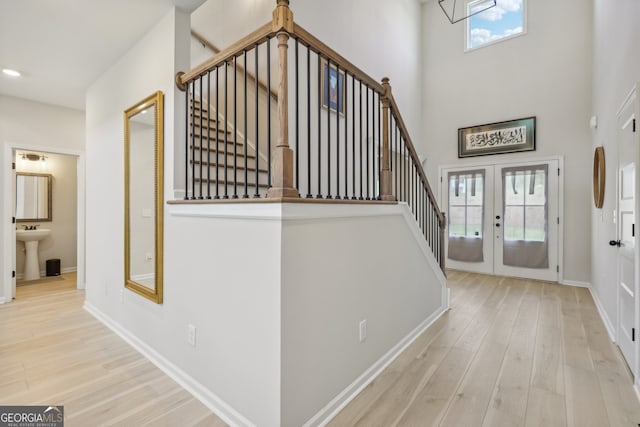 foyer entrance featuring french doors, light hardwood / wood-style floors, a high ceiling, and a wealth of natural light