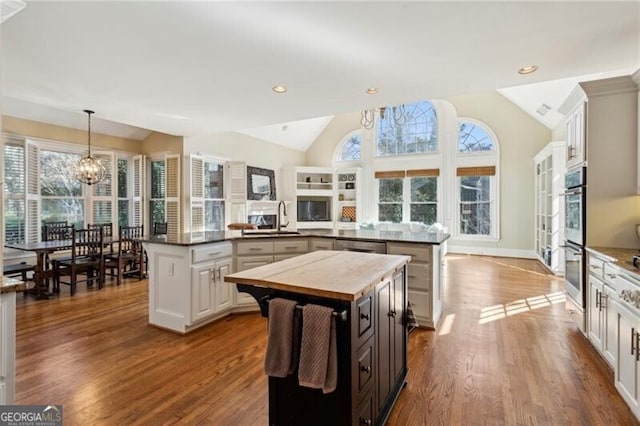 kitchen featuring a center island, kitchen peninsula, vaulted ceiling, and white cabinets