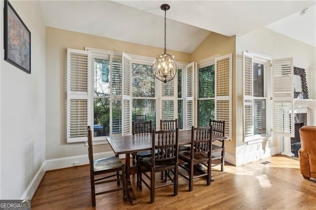 dining area with hardwood / wood-style flooring, lofted ceiling, and an inviting chandelier