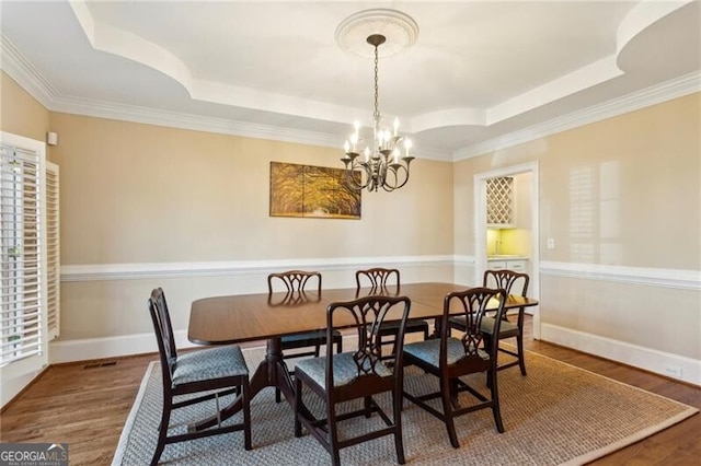 dining room featuring an inviting chandelier, hardwood / wood-style flooring, and a raised ceiling