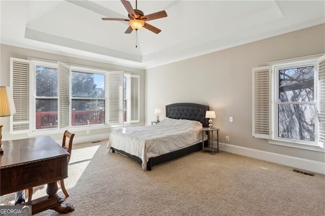 bedroom with multiple windows, a tray ceiling, crown molding, and carpet