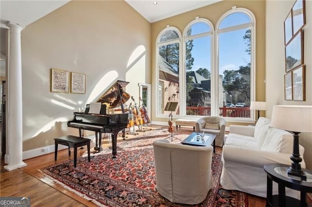 sitting room with ornate columns, wood-type flooring, and vaulted ceiling