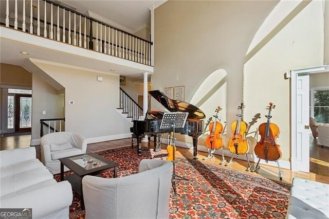 living room with hardwood / wood-style floors, ornamental molding, and a high ceiling