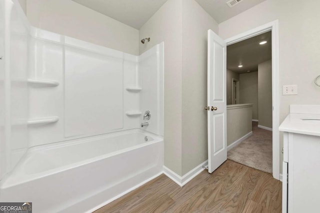 bathroom with hardwood / wood-style flooring, vanity, and bathing tub / shower combination