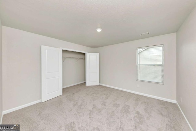 unfurnished bedroom with a closet and light carpet