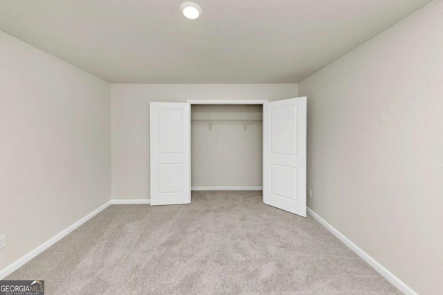 unfurnished bedroom with light colored carpet and a closet