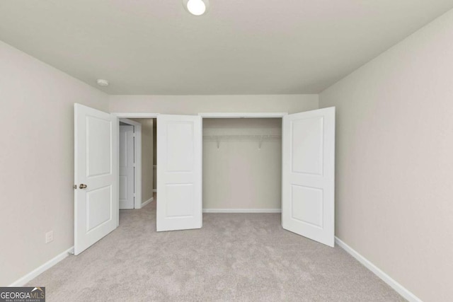 unfurnished bedroom featuring light carpet and a closet