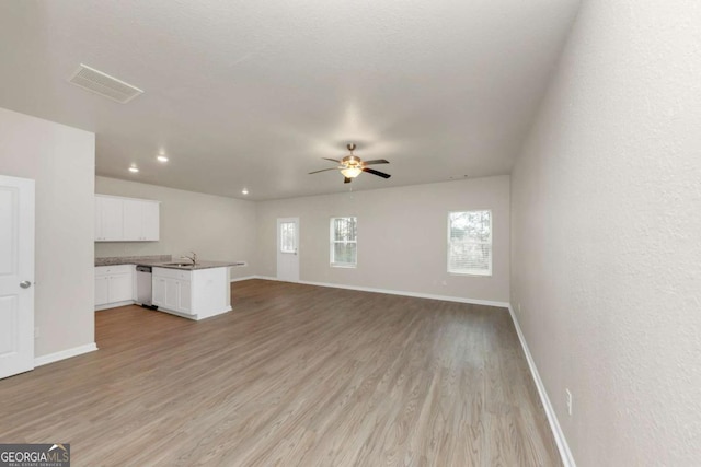 unfurnished living room featuring sink, light hardwood / wood-style floors, and ceiling fan