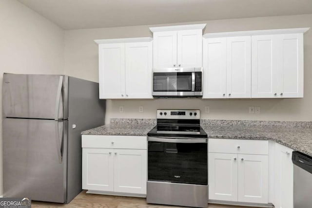 kitchen with white cabinetry, stainless steel appliances, and light stone counters