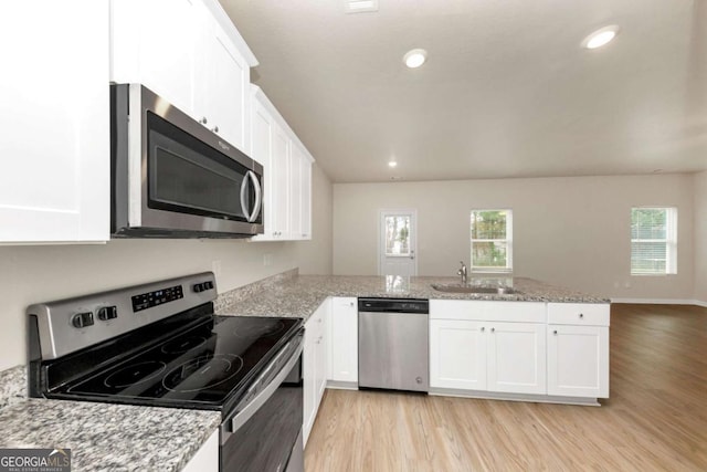 kitchen with stainless steel appliances, white cabinetry, sink, and kitchen peninsula