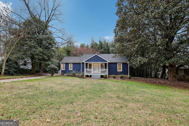 ranch-style house featuring a porch, a shingled roof, a chimney, and a front lawn