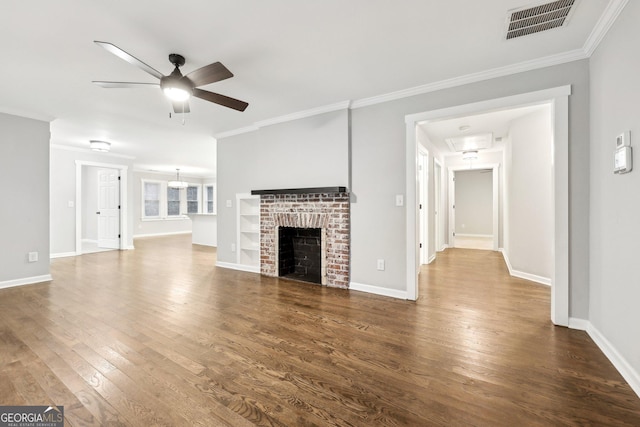 unfurnished living room featuring dark wood-type flooring, a brick fireplace, visible vents, and crown molding