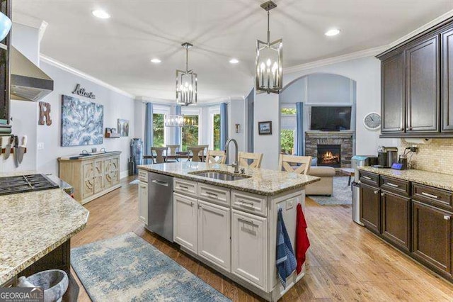 kitchen with appliances with stainless steel finishes, pendant lighting, an island with sink, sink, and dark brown cabinetry