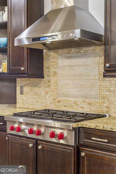 kitchen with light stone counters, decorative backsplash, ventilation hood, and stainless steel gas cooktop