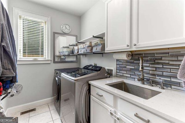 washroom featuring cabinets, independent washer and dryer, sink, and light tile patterned floors