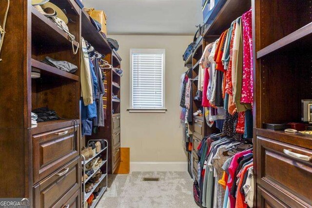 spacious closet featuring light colored carpet