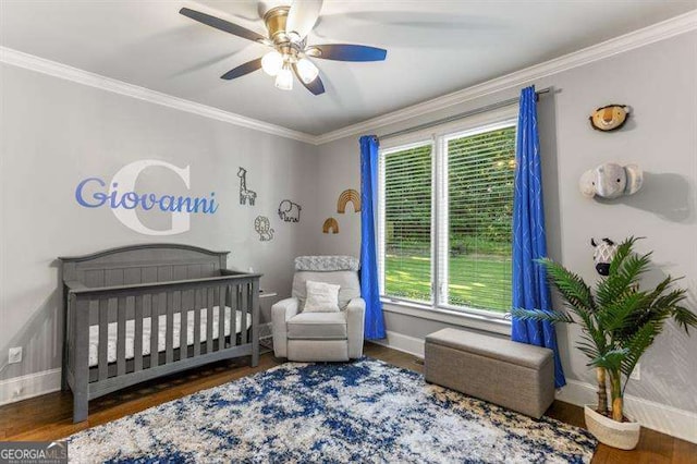 bedroom featuring a nursery area, ceiling fan, ornamental molding, and dark hardwood / wood-style floors