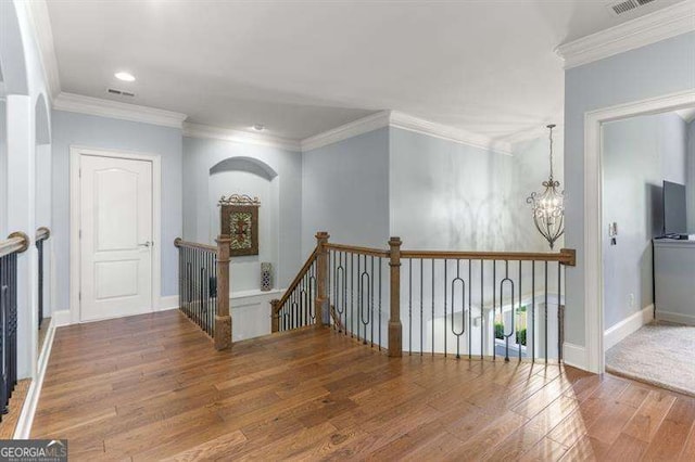 hallway with crown molding, hardwood / wood-style flooring, and a chandelier