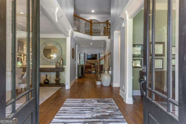 foyer featuring ornamental molding, dark hardwood / wood-style floors, and a high ceiling