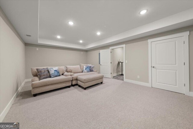 home theater room with light colored carpet and a tray ceiling