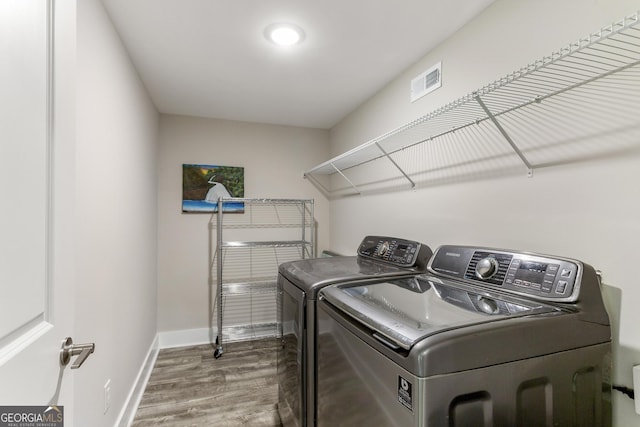 clothes washing area with hardwood / wood-style flooring and washing machine and clothes dryer