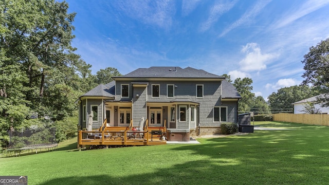 rear view of property featuring a wooden deck, a jacuzzi, and a lawn