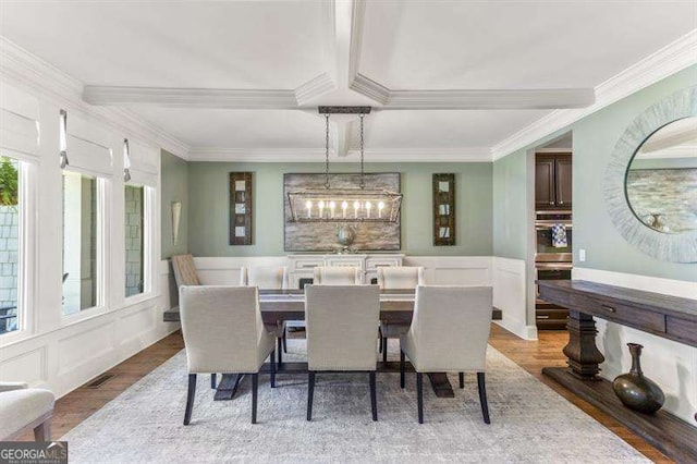 dining space featuring beamed ceiling, crown molding, and hardwood / wood-style floors