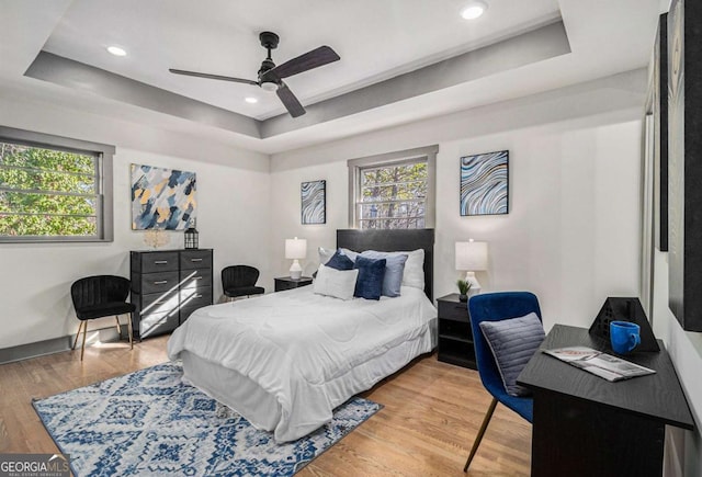 bedroom featuring hardwood / wood-style floors, a raised ceiling, and ceiling fan