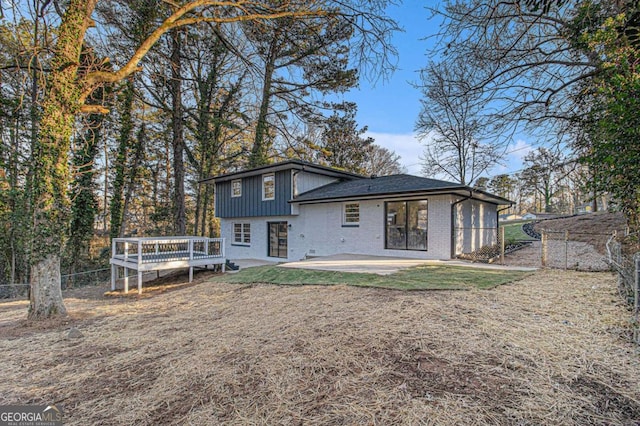 back of property with a wooden deck and a patio area