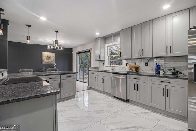 kitchen with sink, gray cabinets, dark stone countertops, hanging light fixtures, and stainless steel dishwasher