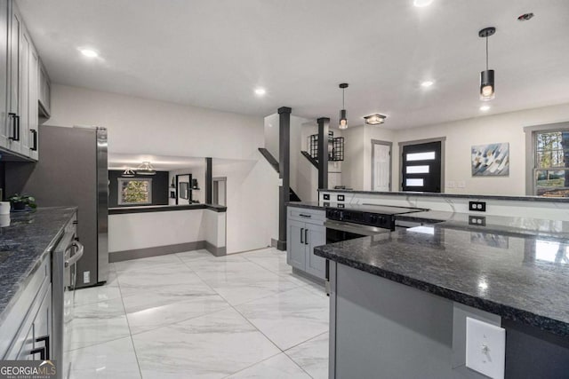 kitchen with plenty of natural light, gray cabinetry, dark stone counters, and decorative light fixtures