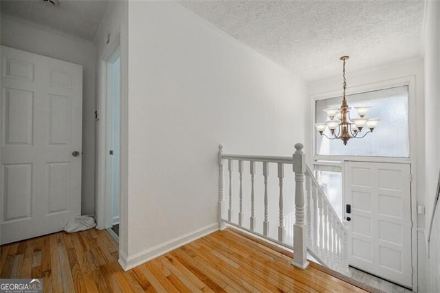 foyer entrance with an inviting chandelier, hardwood / wood-style floors, and a textured ceiling