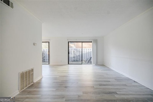 spare room with a textured ceiling and light hardwood / wood-style flooring