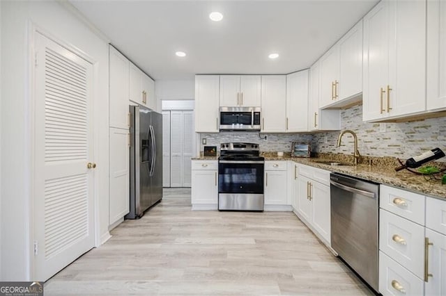 kitchen featuring white cabinetry, stainless steel appliances, sink, and light stone counters