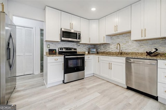 kitchen featuring sink, stainless steel appliances, light stone counters, tasteful backsplash, and white cabinets