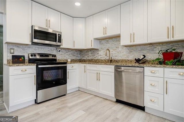 kitchen with light stone countertops, stainless steel appliances, and white cabinets