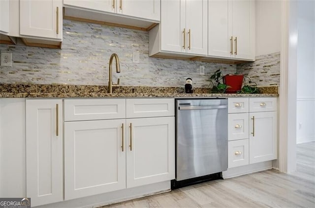 kitchen featuring dark stone countertops, stainless steel dishwasher, and white cabinets