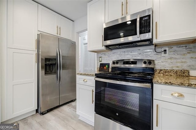 kitchen featuring appliances with stainless steel finishes, white cabinets, light stone counters, and decorative backsplash