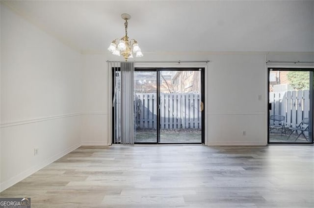 unfurnished dining area with a chandelier, a wealth of natural light, and light wood-type flooring