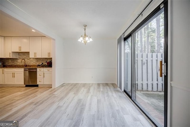 kitchen with white cabinetry, hanging light fixtures, dishwasher, light hardwood / wood-style floors, and decorative backsplash