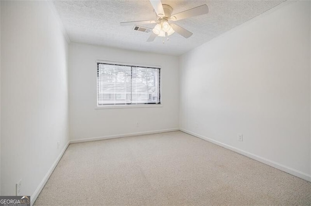 spare room with ceiling fan, light colored carpet, and a textured ceiling