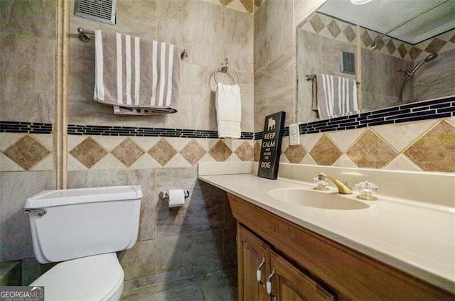 bathroom with vanity, tile walls, and toilet