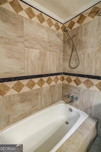 bathroom with tiled shower / bath and a textured ceiling