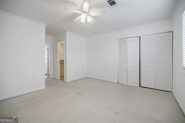 unfurnished bedroom with crown molding, light carpet, ceiling fan, and a closet