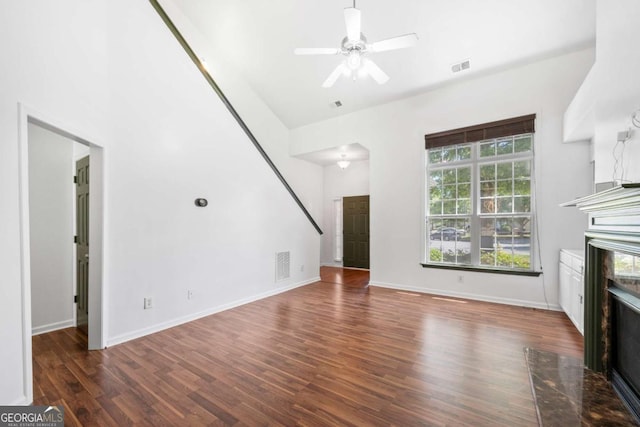 unfurnished living room with dark wood-type flooring, ceiling fan, and a fireplace