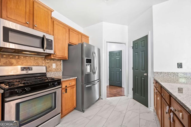 kitchen with light stone counters, appliances with stainless steel finishes, and backsplash