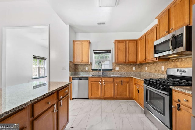 kitchen featuring light stone counters, sink, backsplash, and stainless steel appliances