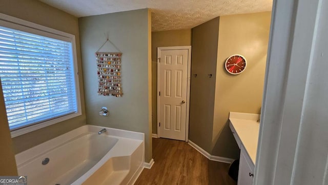 bathroom featuring vanity, wood-type flooring, a bathtub, and a textured ceiling