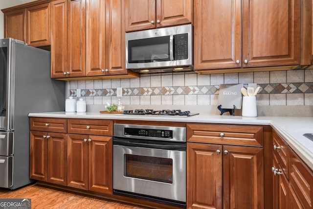 kitchen featuring appliances with stainless steel finishes, light wood-type flooring, and backsplash