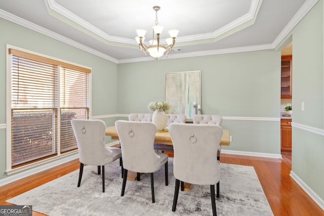 dining area featuring a raised ceiling, crown molding, hardwood / wood-style floors, and a chandelier